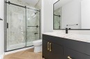 Bathroom featuring a shower with a sliding glass door and marble-patterned wall, a toilet, a vanity with a white countertop, and a mirror with a black frame - 156 Wyatt Ridge, Fort Saskatchewan, AB  - Indoor Photo Showing Bathroom 