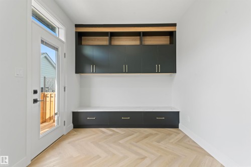 This entryway features herringbone-patterned flooring, built-in dark cabinetry with a light-colored countertop, and a glass-paneled door - 156 Wyatt Ridge, Fort Saskatchewan, AB - Indoor Photo Showing Other Room
