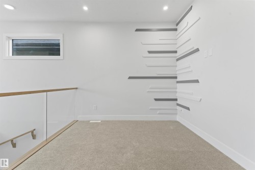 The property features a bright interior space with light-colored carpeting, a contemporary wall design element, and a window providing natural light - 156 Wyatt Ridge, Fort Saskatchewan, AB - Indoor Photo Showing Other Room