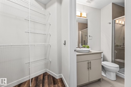 This space features a well-organized closet with wire shelving, durable wood-look flooring, and a bathroom with a modern vanity, vessel sink, and a glass-enclosed shower - 212 10611 117 Street, Edmonton, AB - Indoor