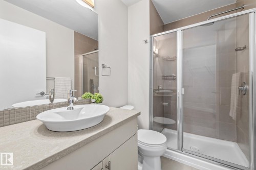Bathroom featuring a vessel sink set on a countertop, a shower with a glass enclosure, and tiled walls - 212 10611 117 Street, Edmonton, AB - Indoor Photo Showing Bathroom