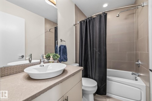 The bathroom features a vessel sink, a vanity with a light-colored countertop, and a tiled shower with a bathtub - 212 10611 117 Street, Edmonton, AB - Indoor Photo Showing Bathroom