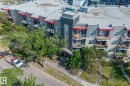 The property features a multi-story building with balconies, a paved sidewalk, and mature trees - 212 10611 117 Street, Edmonton, AB  - Outdoor With Balcony With View 