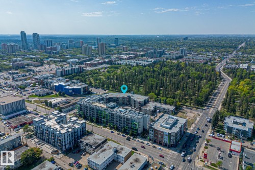 Aerial view of the property and its surrounding community, featuring a mix of modern residential buildings, commercial establishments, and verdant tree-lined streets - 212 10611 117 Street, Edmonton, AB - Outdoor With View