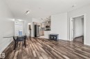 The open concept living area features rich wood-look flooring and light-colored walls - 212 10611 117 Street, Edmonton, AB  - Indoor 