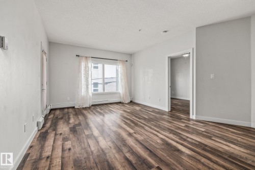 This room features wood-style flooring and light-colored walls - 212 10611 117 Street, Edmonton, AB - Indoor Photo Showing Other Room