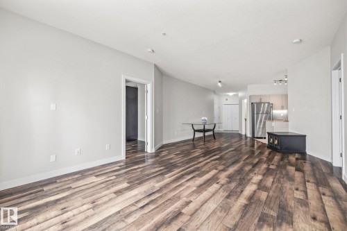 Expansive living area featuring hardwood flooring and a view towards the kitchen with stainless steel appliances - 212 10611 117 Street, Edmonton, AB - Indoor Photo Showing Other Room