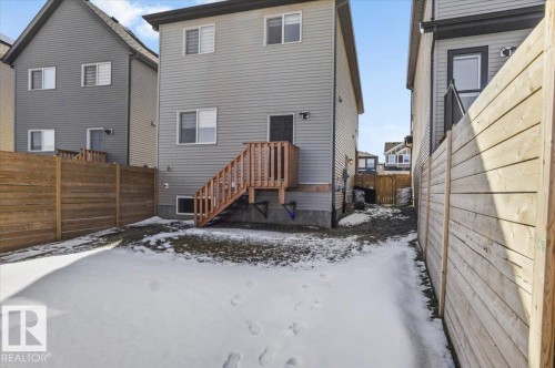 The property features a private yard with wooden fencing and a wooden deck with stairs leading to a back door - 204 Charlesworth Drive, Edmonton, AB - Outdoor With Exterior
