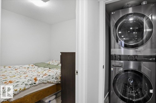 Compact laundry closet with a stacked washer and dryer, providing essential utility - 204 Charlesworth Drive, Edmonton, AB - Indoor Photo Showing Laundry Room