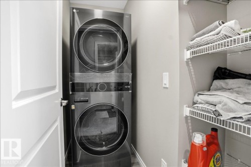 Laundry area featuring a stacked washer and dryer unit, and white wire shelving - 204 Charlesworth Drive, Edmonton, AB - Indoor Photo Showing Laundry Room