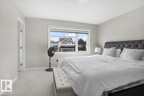 This bedroom features a light neutral color palette, a window with a view of other properties, and light-colored carpeting - 204 Charlesworth Drive, Edmonton, AB - Indoor Photo Showing Bedroom