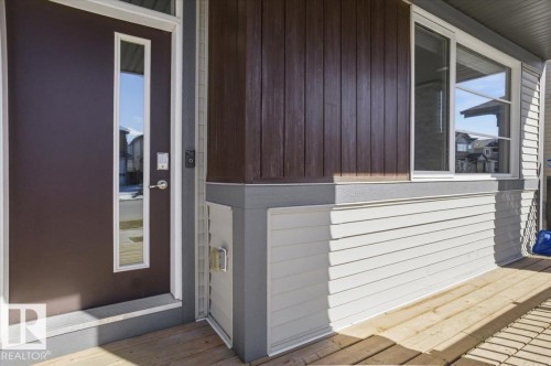 Inviting front entry featuring a brown door with a vertical window, complemented by white siding and brown vertical paneling on the exterior - 204 Charlesworth Drive, Edmonton, AB - Outdoor With Exterior