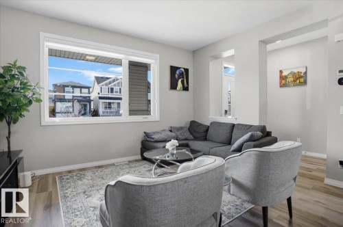 Living area featuring light gray walls, a window with blinds providing natural light, and light wood-style flooring - 204 Charlesworth Drive, Edmonton, AB - Indoor Photo Showing Living Room