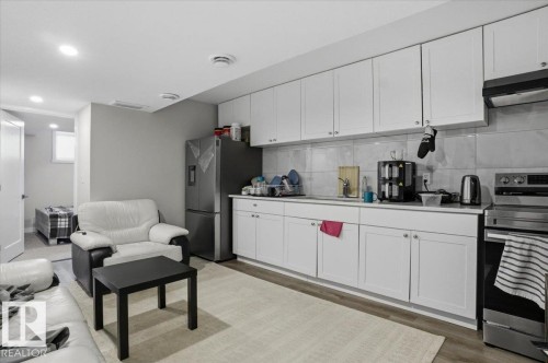 The property features a kitchen area with white cabinetry, a stainless steel refrigerator, and a stainless steel range - 204 Charlesworth Drive, Edmonton, AB - Indoor Photo Showing Kitchen