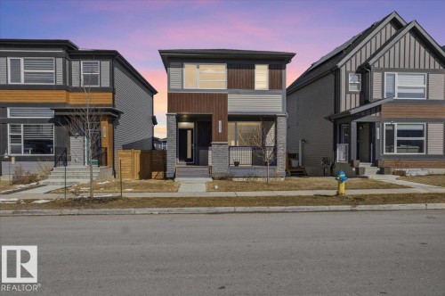 The property features a contemporary architectural style with varied siding textures and colors, including wood and grey panels - 204 Charlesworth Drive, Edmonton, AB - Outdoor With Facade
