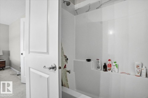Bathroom with a white bathtub and shower combination, featuring a shower head and a built-in shelf - 204 Charlesworth Drive, Edmonton, AB - Indoor