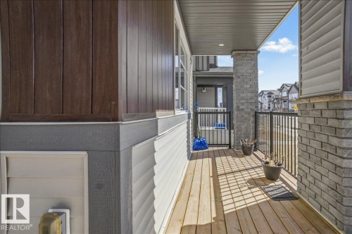 The property features a spacious porch with wooden decking, brick columns, and a black metal railing - 204 Charlesworth Drive, Edmonton, AB - Outdoor With Exterior