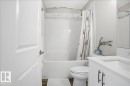 This bathroom features a white bathtub with a shower, a toilet, and a vanity with a sink and white countertop - 204 Charlesworth Drive, Edmonton, AB  - Indoor Photo Showing Bathroom 