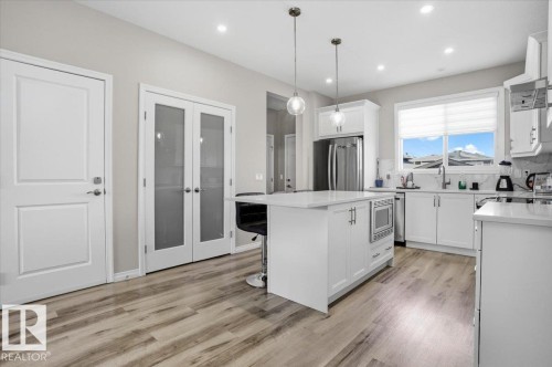 The kitchen features white cabinetry, a central island with a built-in microwave, and stainless steel appliances - 204 Charlesworth Drive, Edmonton, AB - Indoor Photo Showing Kitchen With Upgraded Kitchen