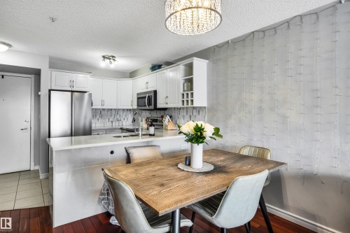Kitchen featuring white cabinetry, stainless steel appliances, a tiled backsplash, and a breakfast bar - 319 17404 64 Avenue, Edmonton, AB - Indoor Photo Showing Dining Room