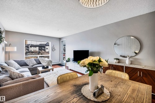 Open concept living area with hardwood flooring and a large window providing views of the exterior - 319 17404 64 Avenue, Edmonton, AB - Indoor Photo Showing Living Room