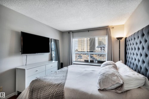 This property features a room with a large window, providing natural light, and a view of surrounding structures - 319 17404 64 Avenue, Edmonton, AB - Indoor Photo Showing Bedroom