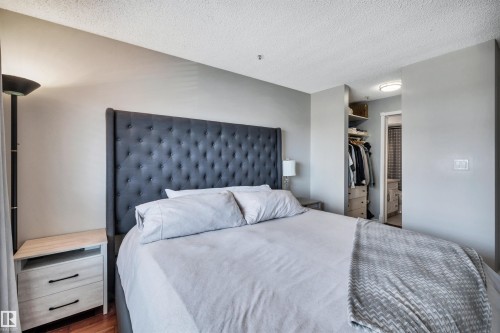 Bedroom featuring hardwood floors, light gray painted walls, and a convenient walk-in closet with shelving - 319 17404 64 Avenue, Edmonton, AB - Indoor Photo Showing Bedroom