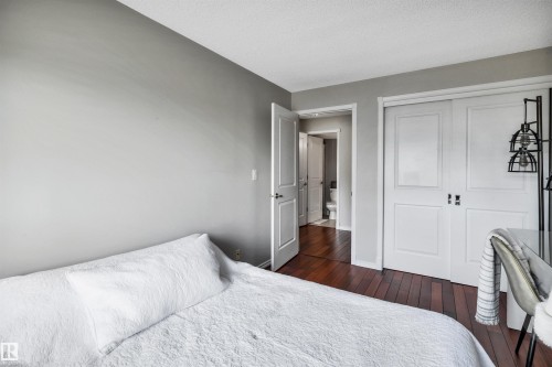 This room features rich hardwood flooring, light grey walls, and white trim - 319 17404 64 Avenue, Edmonton, AB - Indoor Photo Showing Bedroom