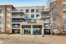 The property features a multi-story building with a prominent main entrance, balconies with railings, and a mix of tan and brown exterior siding - 319 17404 64 Avenue, Edmonton, AB  - Outdoor With Balcony With Facade 