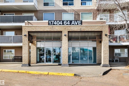 The property features a brick facade on the ground level, large glass entry doors, and a prominent building address display - 319 17404 64 Avenue, Edmonton, AB - Outdoor With Balcony With Facade