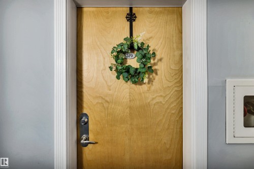 The property features a light-toned wooden door with a dark-toned handle and lock mechanism - 319 17404 64 Avenue, Edmonton, AB - Indoor