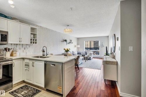 The property features a kitchen with white cabinetry, stainless steel appliances, and a light-colored countertop - 319 17404 64 Avenue, Edmonton, AB - Indoor Photo Showing Kitchen With Double Sink