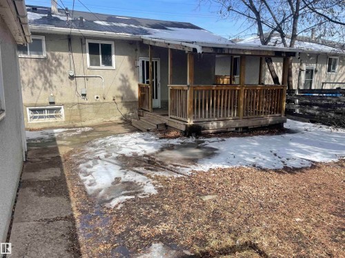 The property features a rear exterior with a wooden deck and covered porch, an exterior access door, and windows - 12335 132 Avenue, Edmonton, AB - Outdoor With Deck Patio Veranda