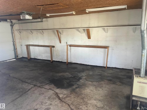 The property features a garage with a concrete floor, overhead lighting, and a garage door mechanism - 12335 132 Avenue, Edmonton, AB - Indoor Photo Showing Garage