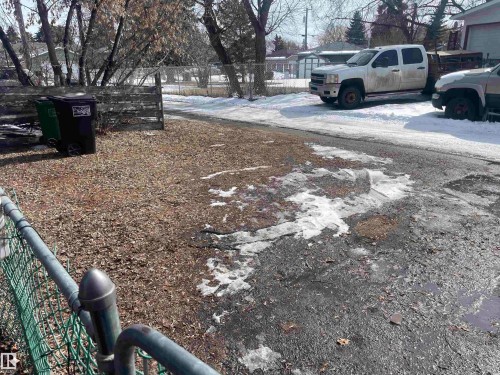 The property features a fenced yard area with a chain-link fence, a wooden fence, and mature trees - 12335 132 Avenue, Edmonton, AB - Outdoor
