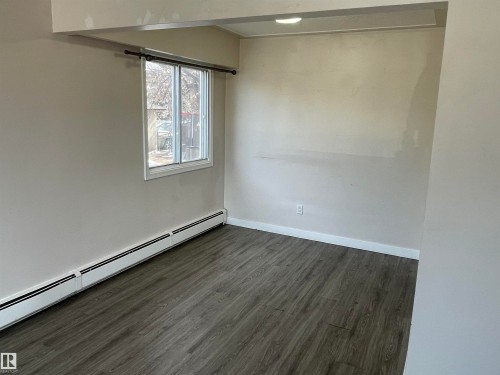 This room features dark-toned flooring, a window providing natural light, and baseboard heating - 12335 132 Avenue, Edmonton, AB - Indoor Photo Showing Other Room