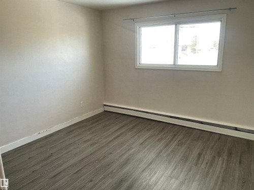 Well-lit room featuring light-colored walls, wood-look flooring, and a window providing natural light - 12335 132 Avenue, Edmonton, AB - Indoor Photo Showing Other Room