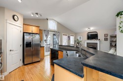 The kitchen features dual stainless steel sinks, dark countertops, and light wood cabinetry, with hardwood flooring extending throughout the space - 