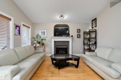 Living area featuring hardwood flooring, a fireplace with a white mantel, and windows with blinds - 