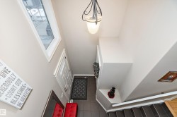 Inviting entryway with a white paneled door, tiled flooring, and a decorative light fixture - 