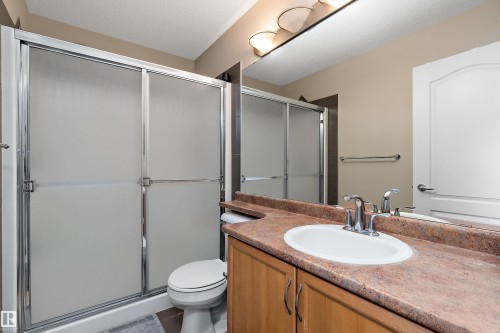 Bathroom featuring a shower with frosted glass doors, a vanity with a white sink, and a large mirror - 16748 118 Street, Edmonton, AB - Indoor Photo Showing Bathroom