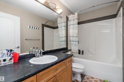 The bathroom features a light brown vanity with a black countertop, a white oval sink with a chrome faucet, and a large mirror - 