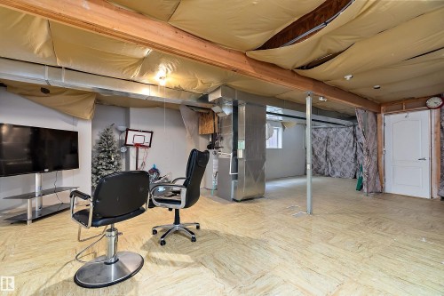 The property features a spacious room with visible ceiling beams and ductwork, offering a unique aesthetic - 16748 118 Street, Edmonton, AB - Indoor Photo Showing Basement