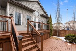 The property features a tiered deck with brown wood planks and black metal railings - 