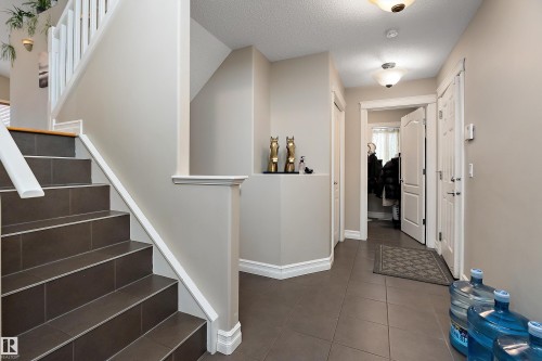 The property features a staircase with dark tile steps and white railings, a hallway with tiled flooring, and light-colored walls throughout - 16748 118 Street, Edmonton, AB - Indoor Photo Showing Other Room