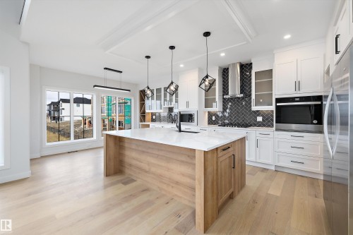 Modern kitchen with a large island featuring a light wood base and a white countertop - 34 Cannes Cove, St. Albert, AB - Indoor Photo Showing Kitchen With Upgraded Kitchen