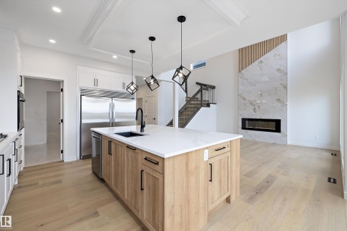 The kitchen features a large island with a sink, stainless steel appliances, and white cabinetry - 34 Cannes Cove, St. Albert, AB - Indoor Photo Showing Kitchen With Upgraded Kitchen