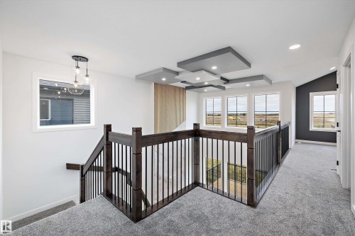 The property features a spacious landing with light grey carpeted flooring and dark wood railing with black spindles - 34 Cannes Cove, St. Albert, AB - Indoor Photo Showing Other Room