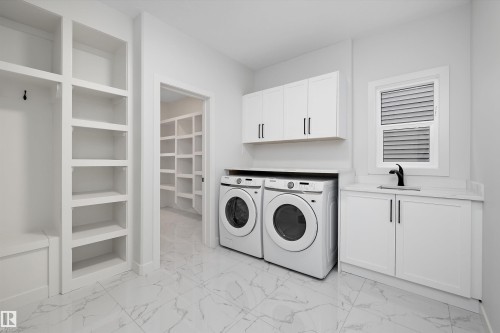 Laundry room featuring white cabinetry, a sink with a black faucet, and a window with blinds - 34 Cannes Cove, St. Albert, AB - Indoor Photo Showing Laundry Room