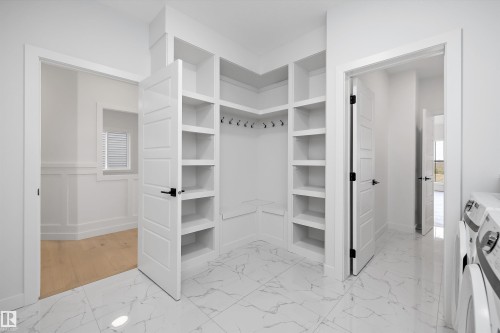 Entryway featuring white built-in shelving, coat hooks, and white marble-look flooring - 34 Cannes Cove, St. Albert, AB - Indoor Photo Showing Laundry Room